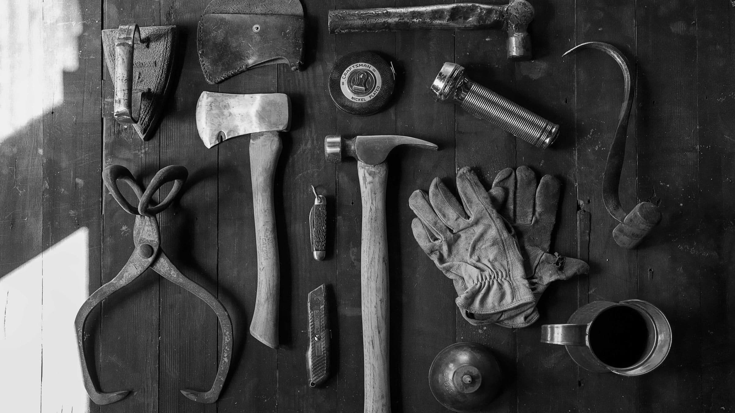 Herramientas de oficio y guantes de trabajo sobre una mesa de madera